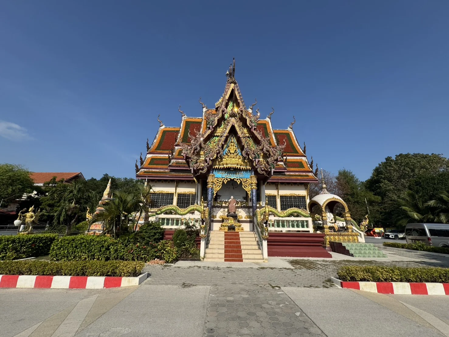 Traditional Thai Buddhist temple building at Wat Plai Laem in Koh Samui, Thailand, surrounded by a peaceful lake and lush green trees.